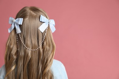 Photo of Cute little girl with beautiful hair accessory on coral background, back view. Space for text