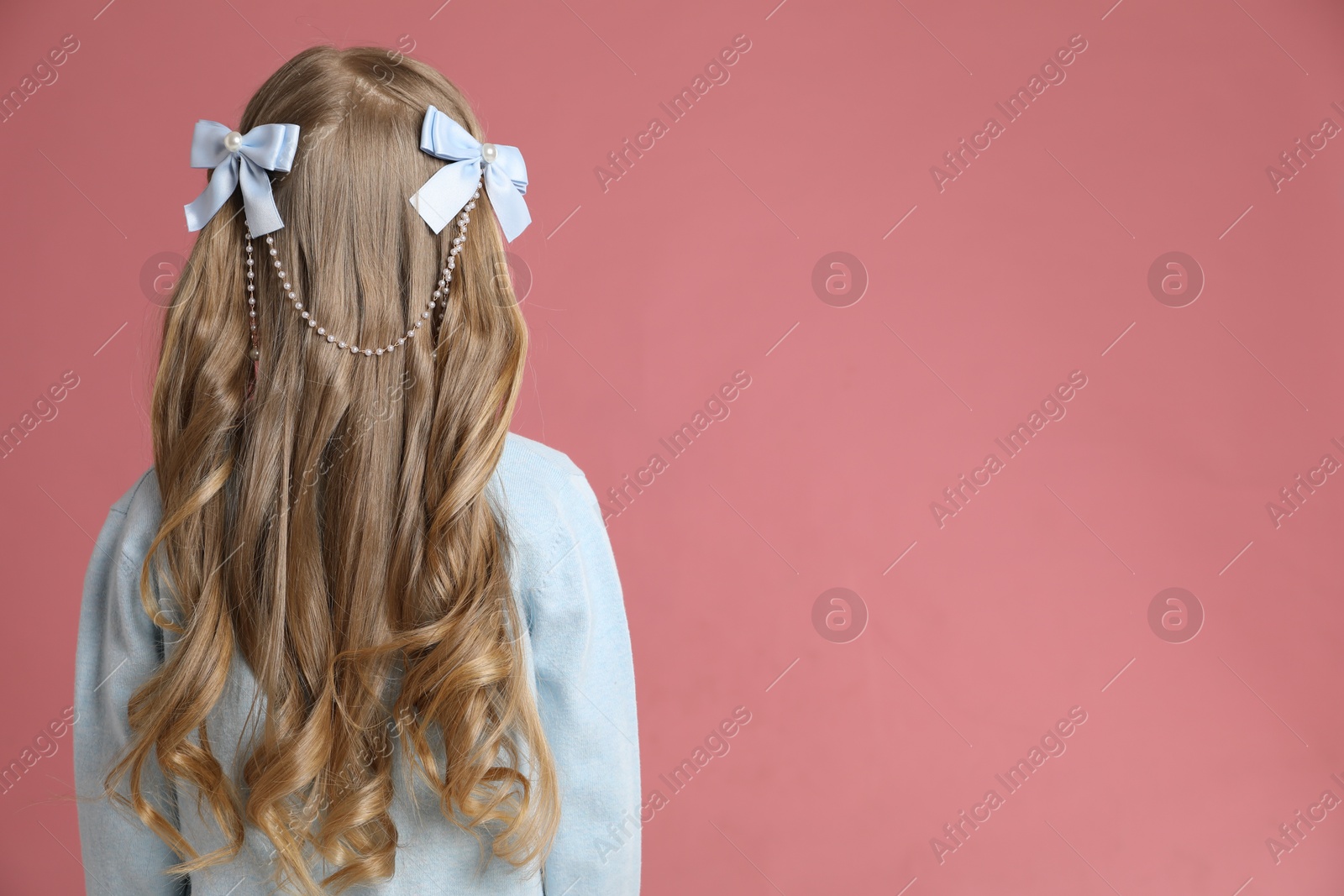 Photo of Cute little girl with beautiful hair accessory on coral background, back view