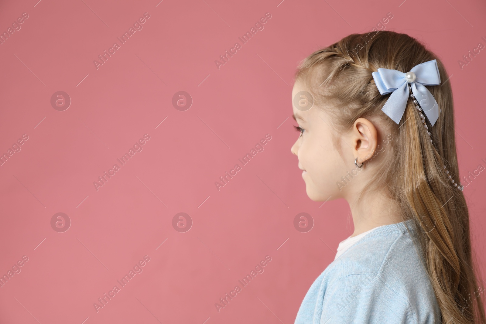 Photo of Cute little girl with beautiful hair accessory on coral background. Space for text