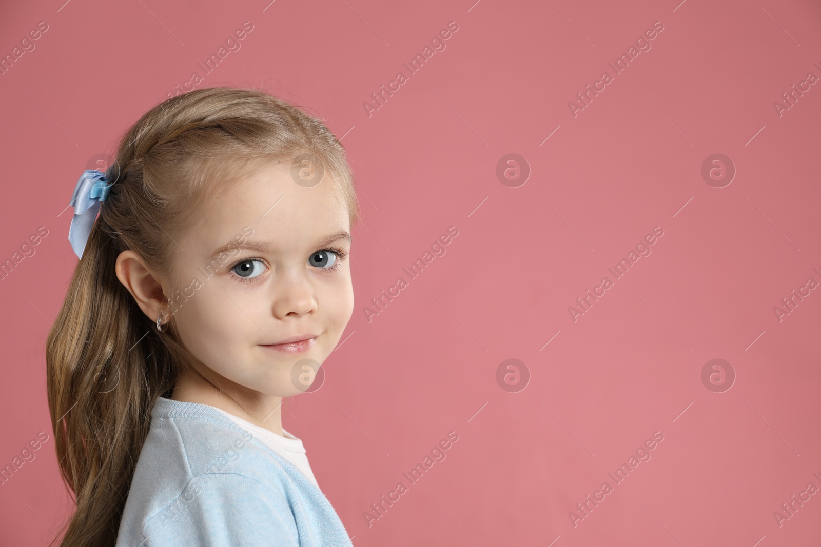 Photo of Cute little girl with beautiful hair accessory on coral background. Space for text