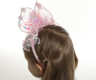 Photo of Cute little girl with beautiful headband on white background, back view