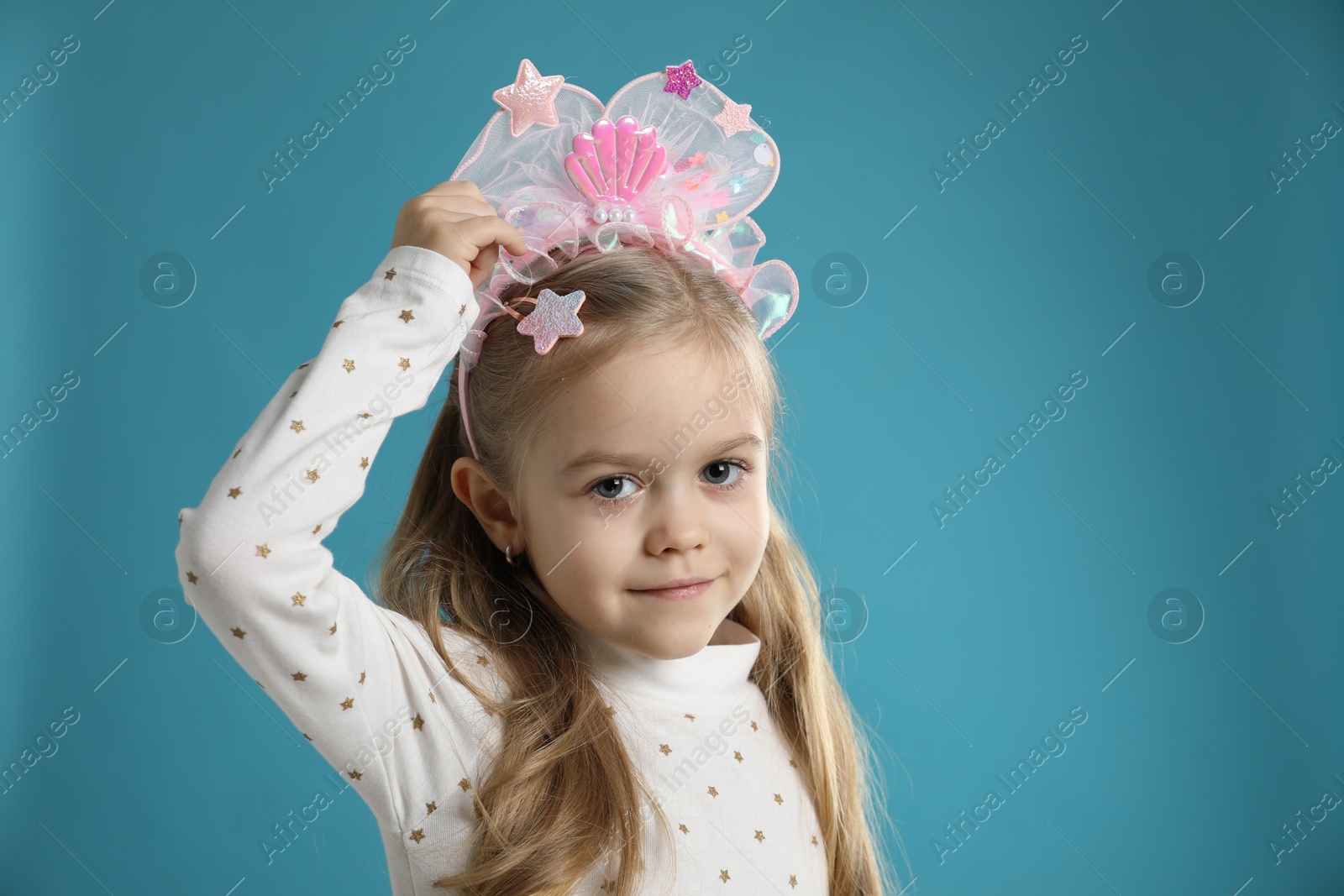 Photo of Cute little girl with beautiful headband on blue background. Space for text