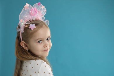 Photo of Cute little girl with beautiful headband on blue background. Space for text