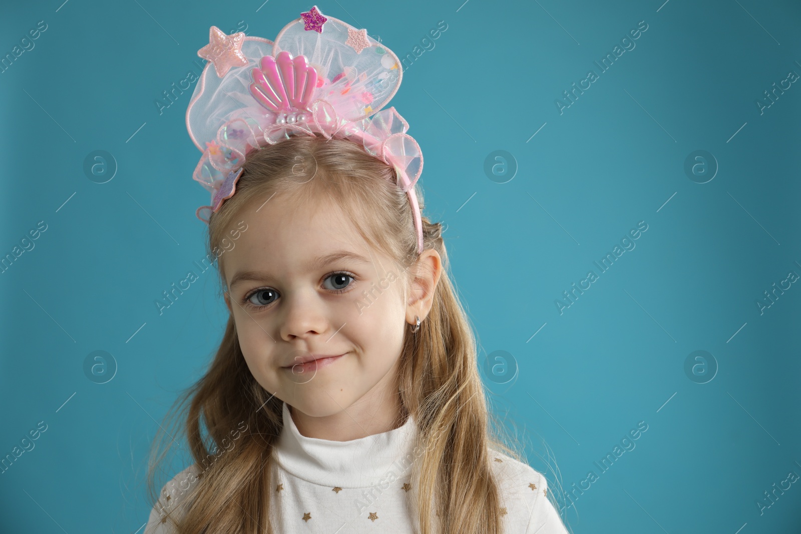 Photo of Cute little girl with beautiful headband on blue background