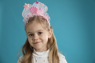 Photo of Cute little girl with beautiful headband on blue background