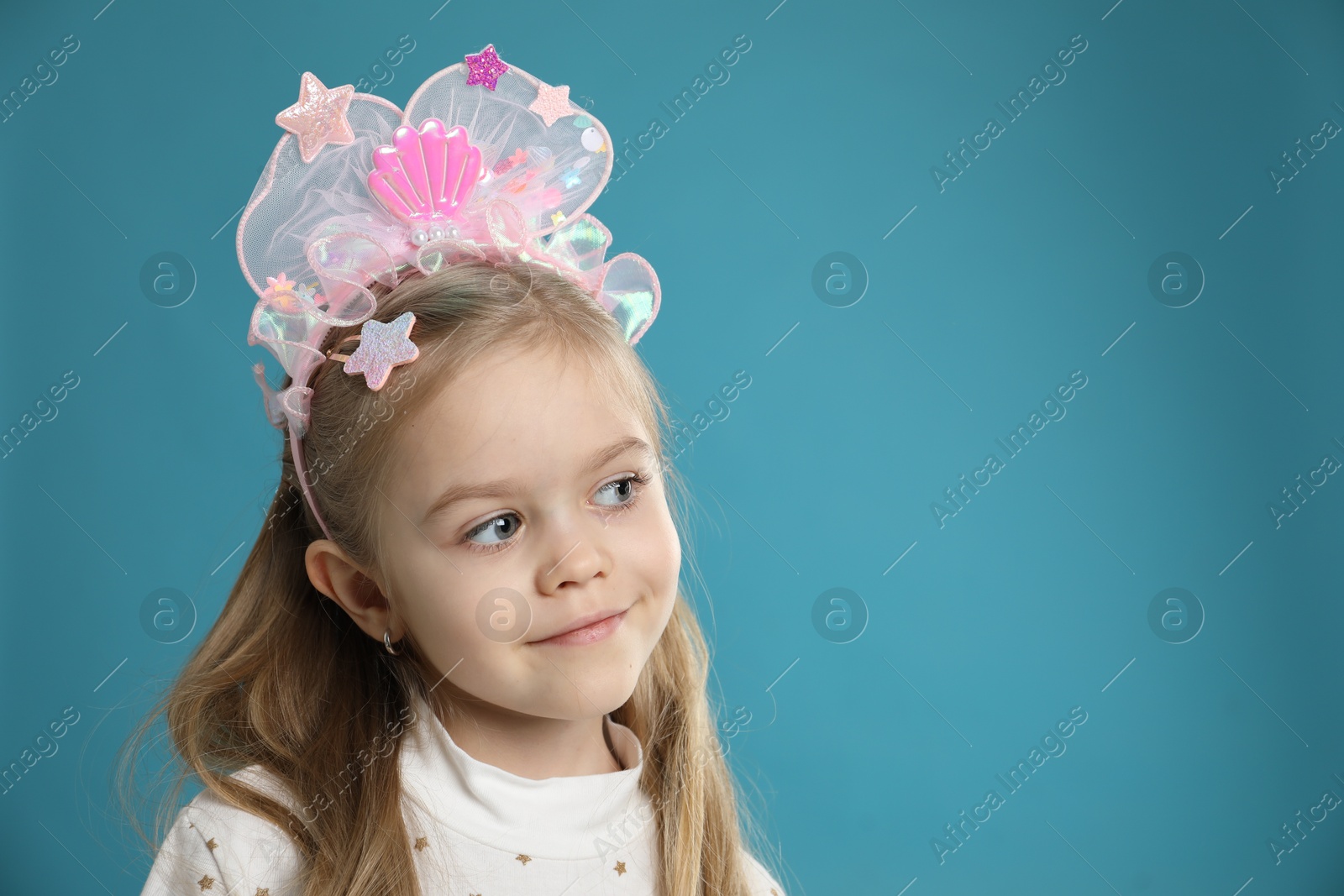 Photo of Cute little girl with beautiful headband on blue background. Space for text