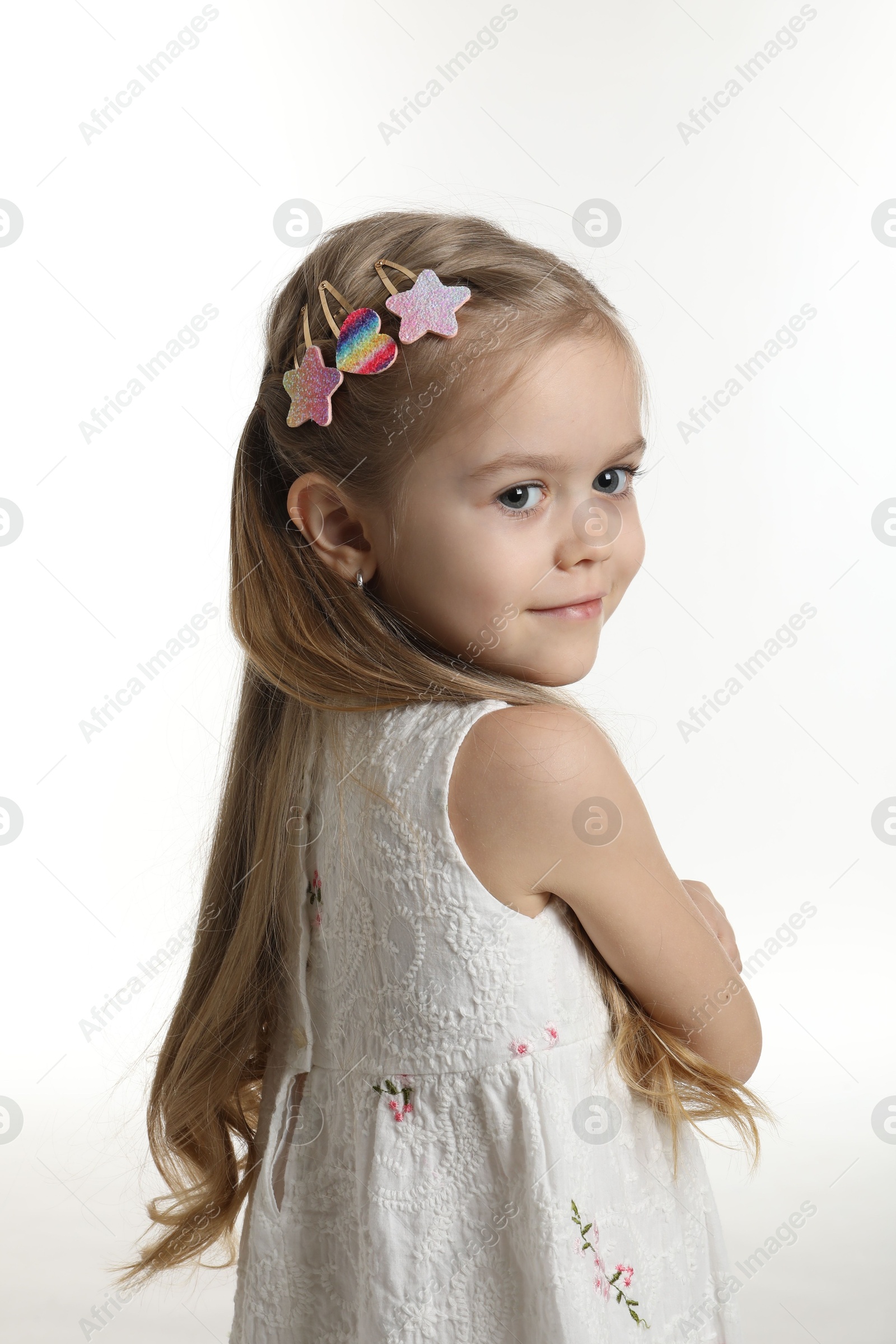 Photo of Cute little girl with beautiful hair clips on white background