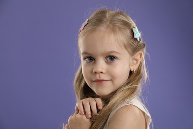 Photo of Cute little girl with beautiful hair clips on violet background