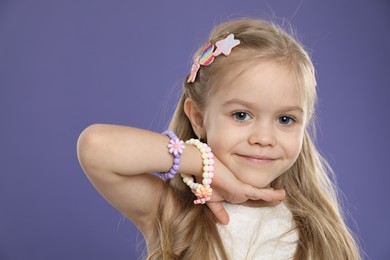 Photo of Cute little girl with beautiful hair clips on violet background