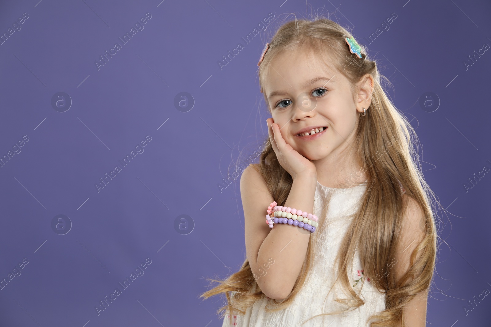 Photo of Cute little girl with beautiful hair clips on violet background. Space for text