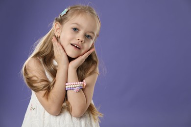 Photo of Cute little girl with beautiful hair clips on violet background. Space for text