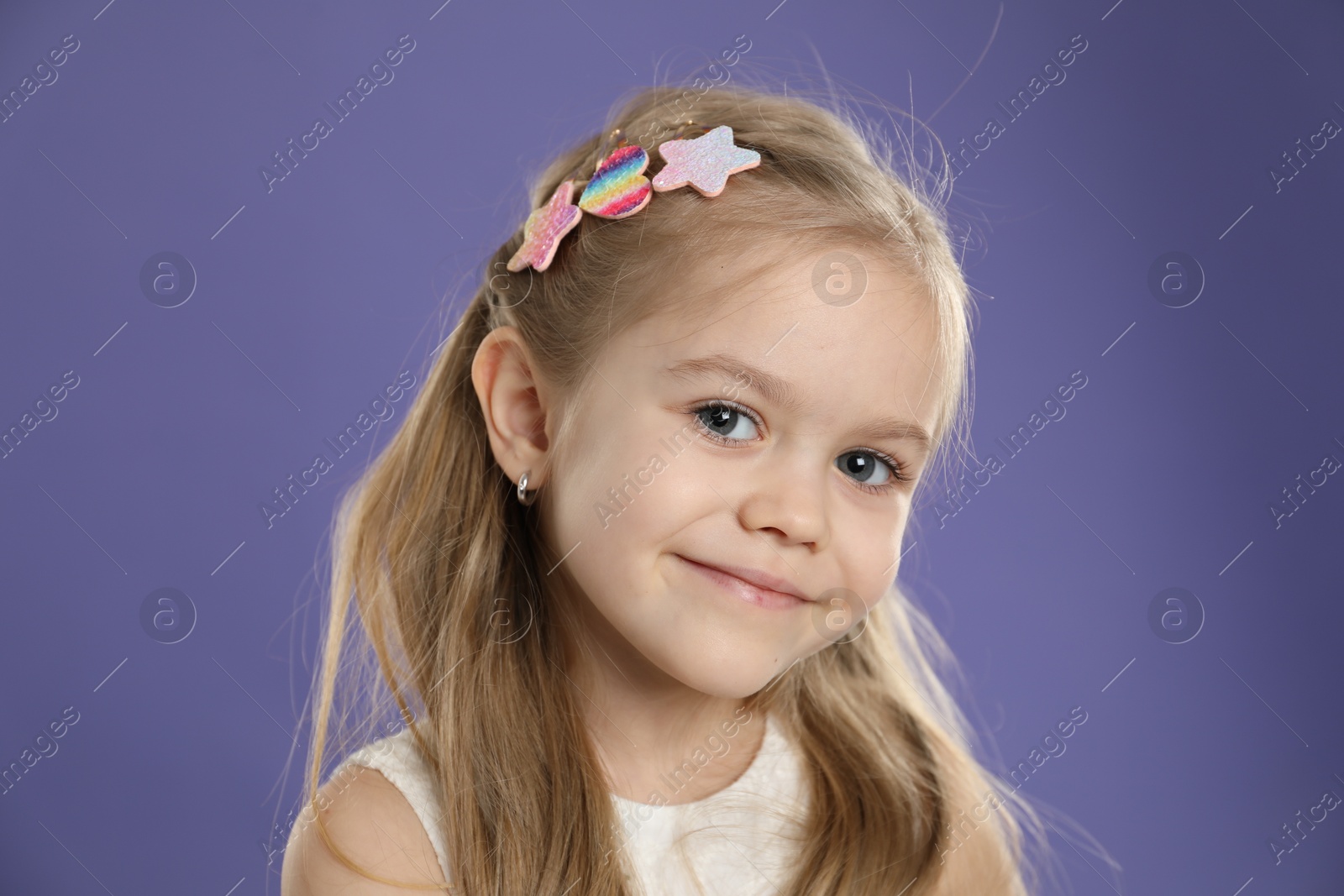 Photo of Cute little girl with beautiful hair clips on violet background