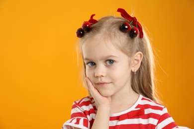 Photo of Cute little girl wearing beautiful bows with cherries on orange background. Space for text