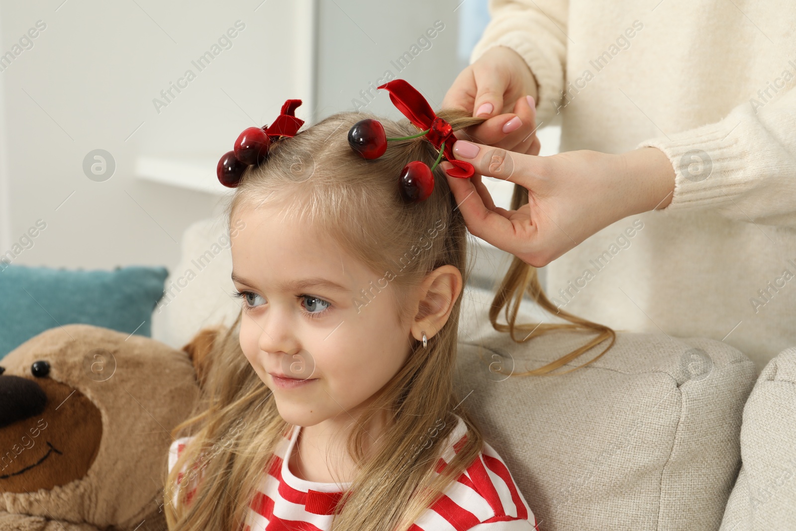 Photo of Mom putting cute accessories onto her daughter's hair at home, closeup