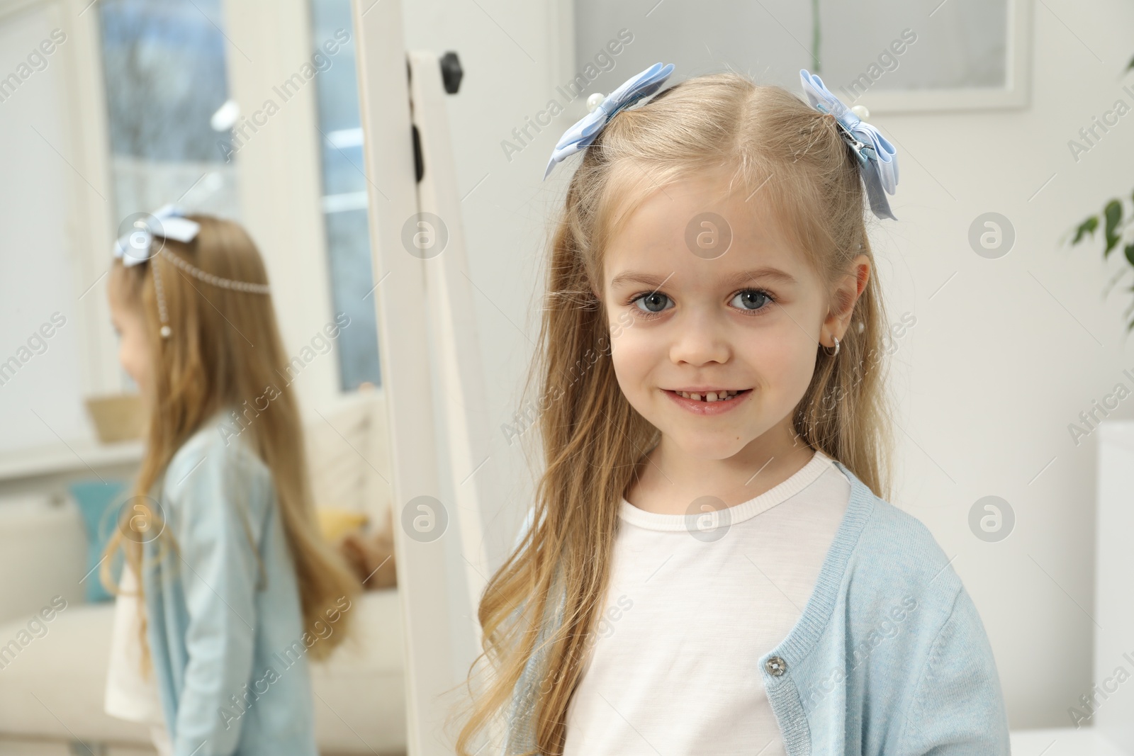 Photo of Cute little girl with beautiful hair accessory at home