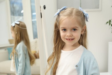 Photo of Cute little girl with beautiful hair accessory at home