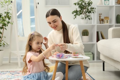 Photo of Mom putting cute accessories onto her daughter's hair at home