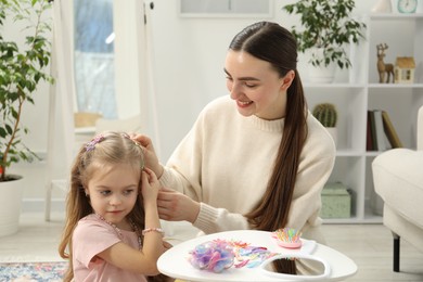 Photo of Mom putting cute accessories onto her daughter's hair at home