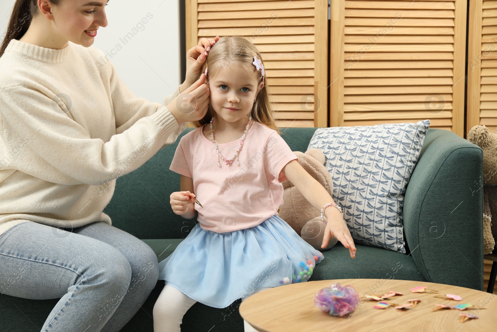 Photo of Mom putting cute accessories onto her daughter's hair at home