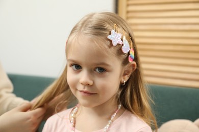 Photo of Mom putting cute accessories onto her daughter's hair at home, closeup