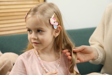 Photo of Mom putting cute accessories onto her daughter's hair at home, closeup