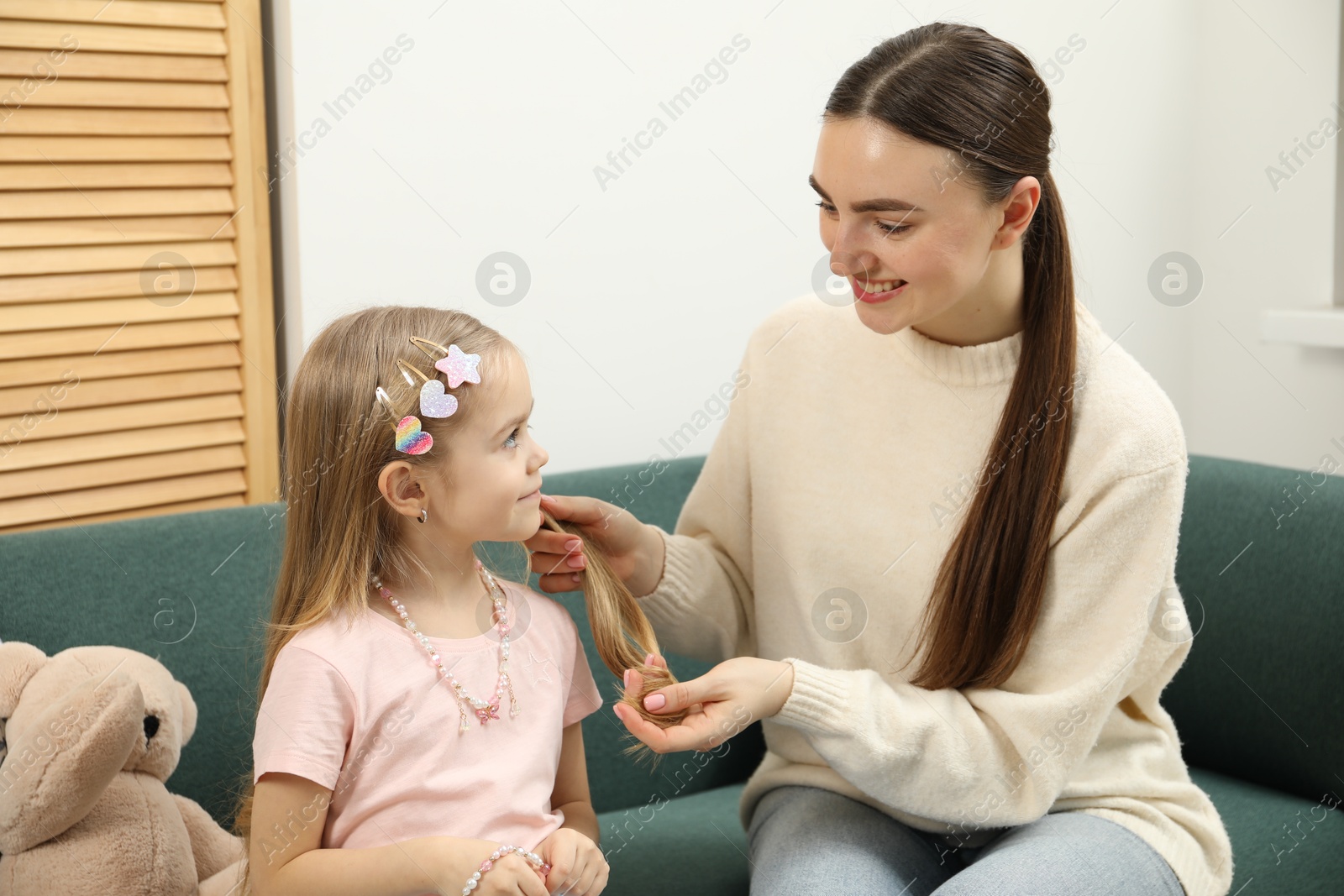 Photo of Mom putting cute accessories onto her daughter's hair at home