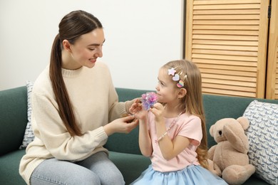 Photo of Mom putting cute accessories onto her daughter's hair at home