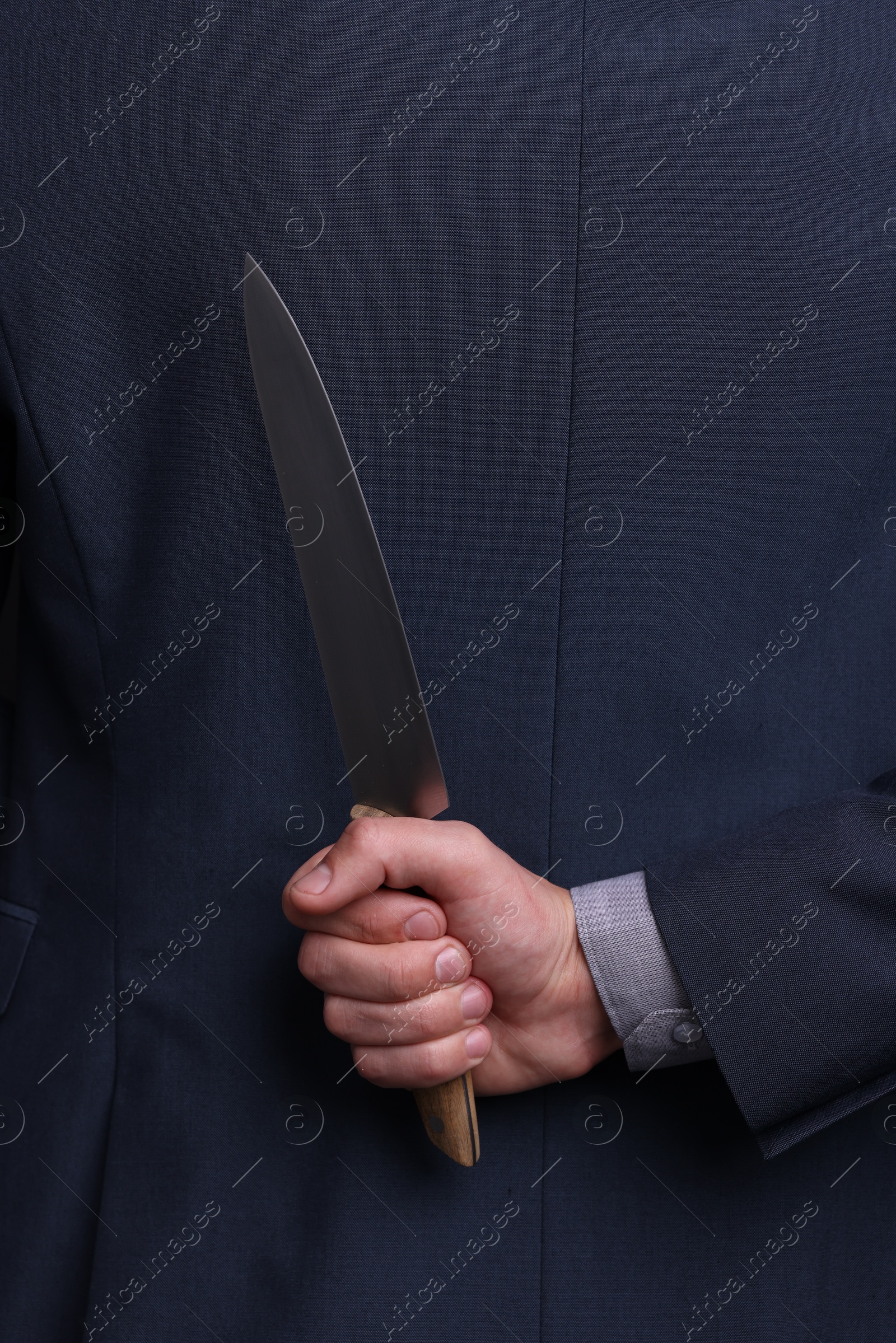 Photo of Businessman holding knife behind his back, closeup