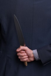 Photo of Businessman holding knife behind his back, closeup