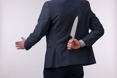 Photo of Businessman holding knife behind his back and offering handshake on white background, closeup