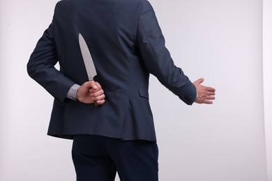 Photo of Businessman holding knife behind his back and offering handshake on white background, closeup