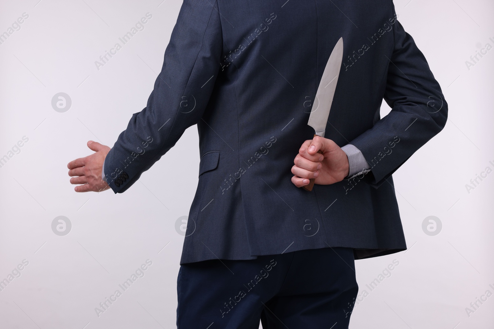 Photo of Businessman holding knife behind his back and offering handshake on white background, closeup