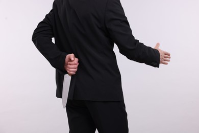 Photo of Businessman holding knife behind his back and offering handshake on white background, closeup