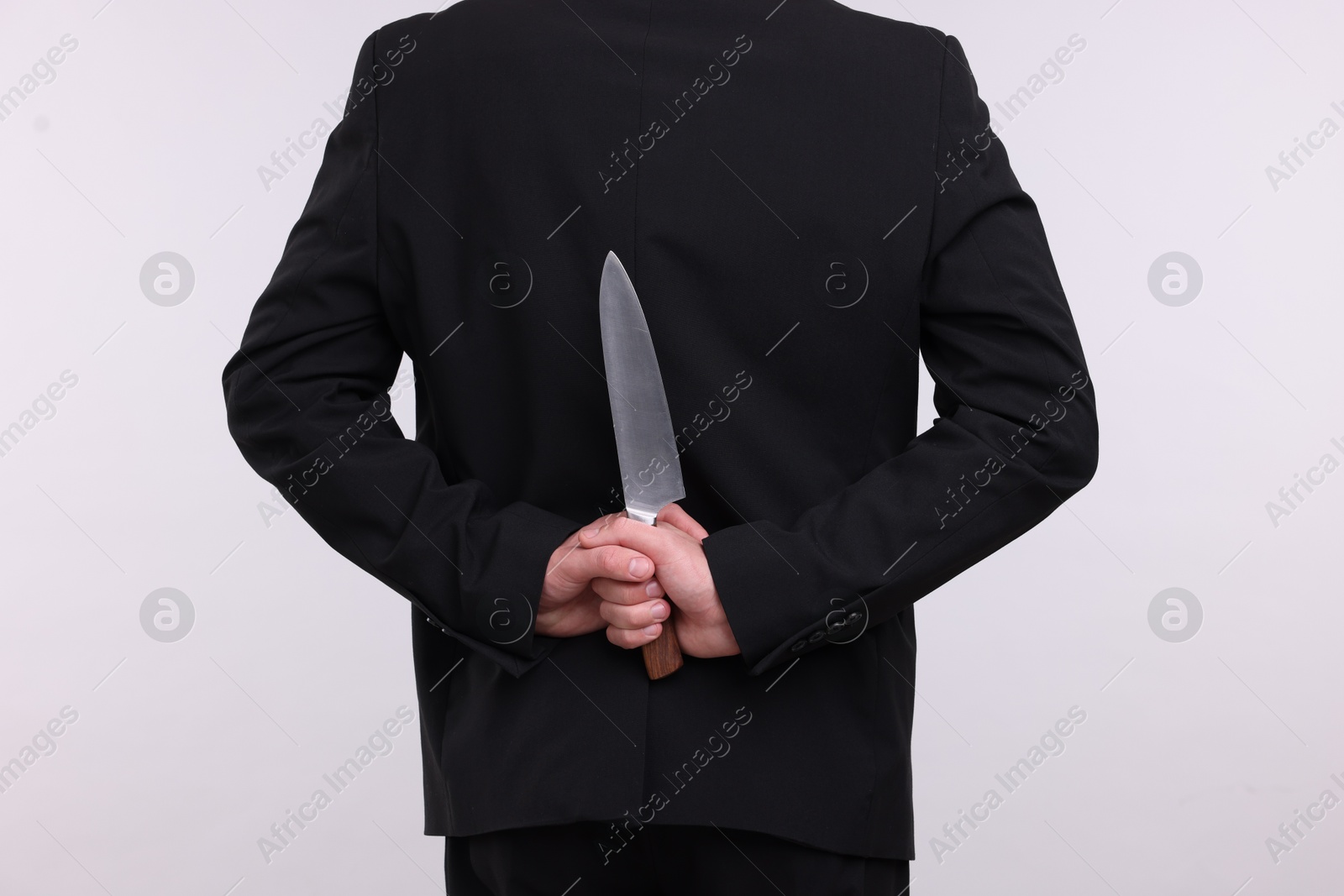 Businessman holding knife behind his back on white background, closeup Photo of Businessman holding knife behind his back on white background, closeup