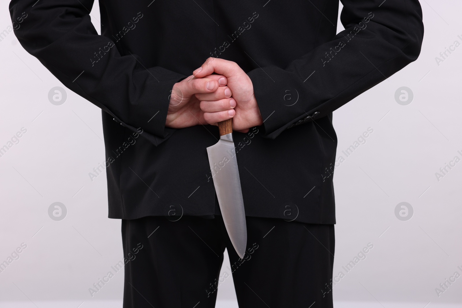 Photo of Businessman holding knife behind his back on white background, closeup