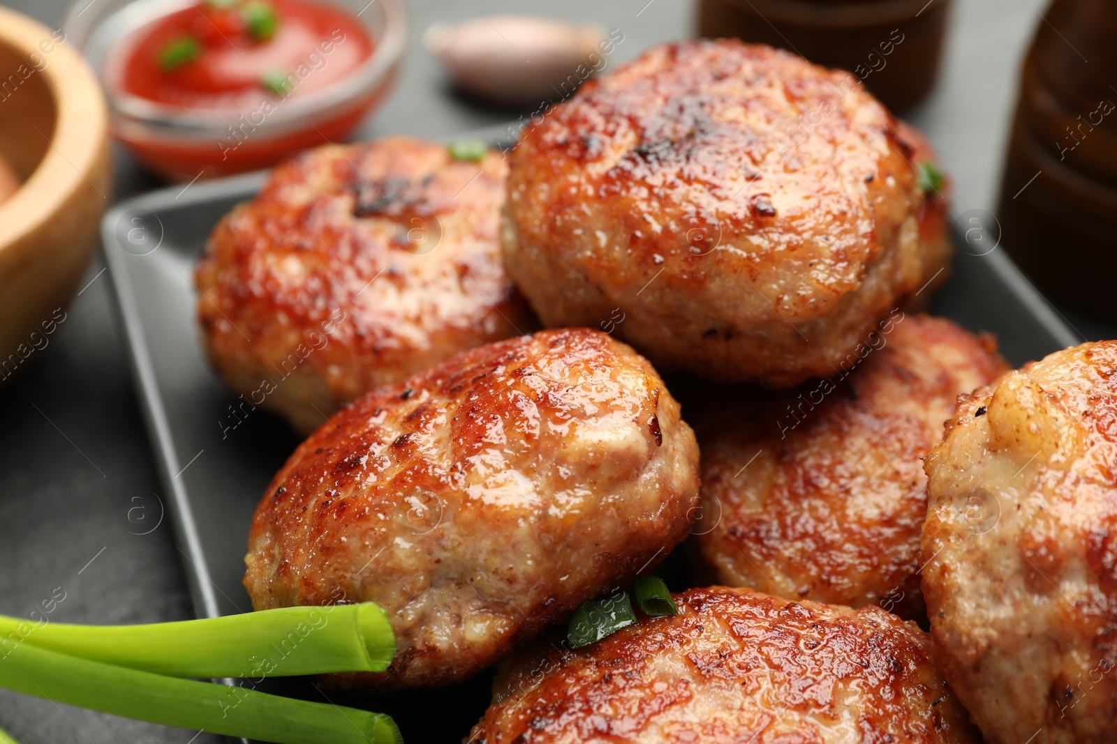 Photo of Delicious patties with green onions on black table, closeup