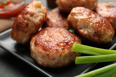 Photo of Delicious patties with green onions on black table, closeup