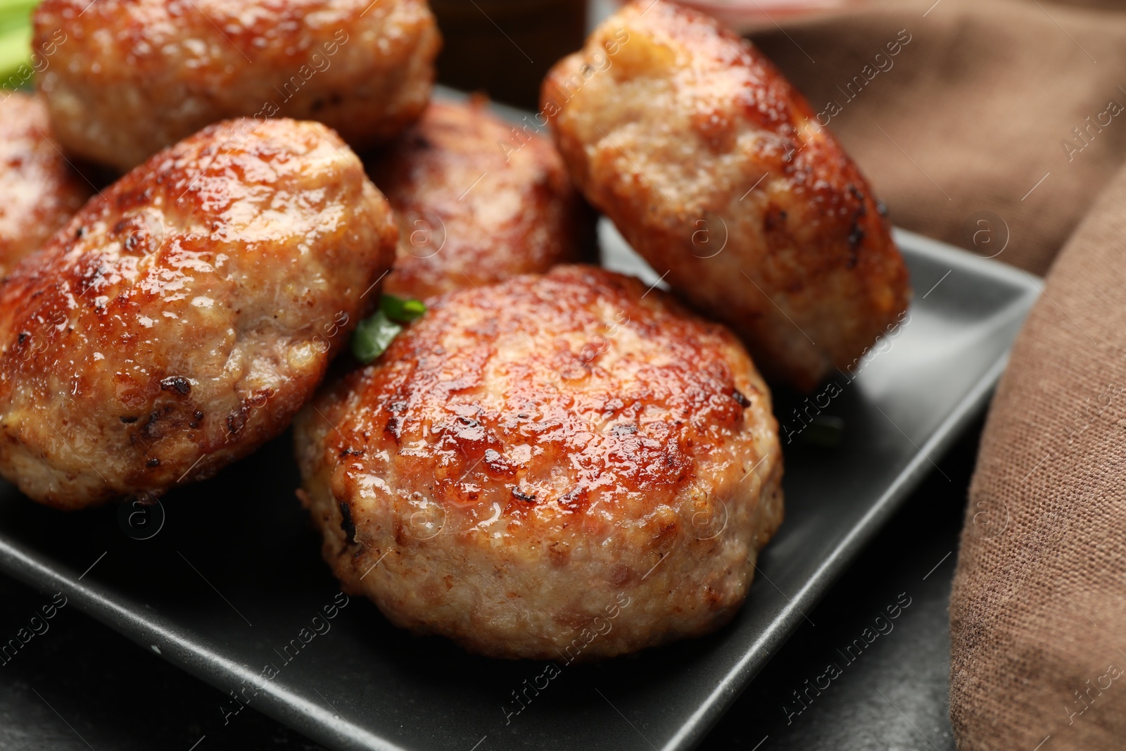 Photo of Delicious roasted patties on black table, closeup