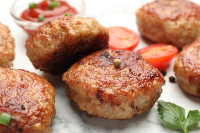 Photo of Delicious patties with sauce, cherry tomatoes and parsley on white marble table, closeup