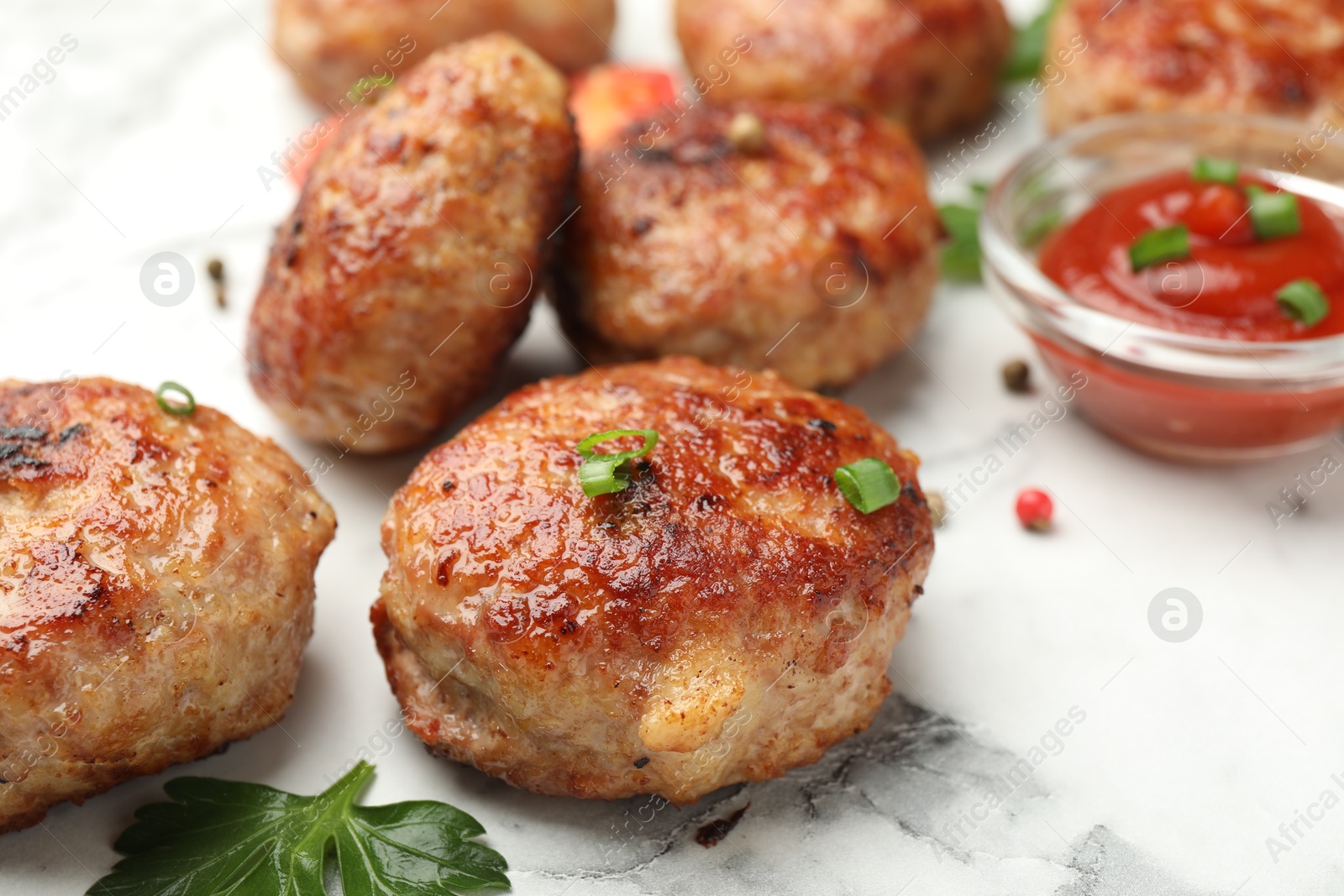 Photo of Delicious patties with sauce and parsley on white marble table, closeup