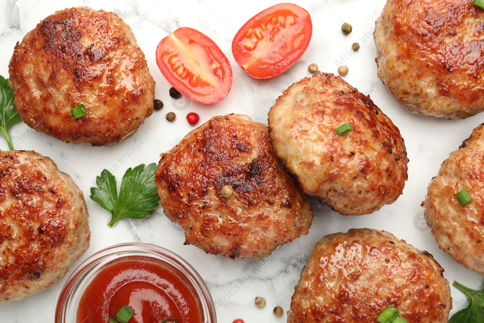 Photo of Delicious patties with sauce, cherry tomatoes, peppercorns and parsley on white marble table, flat lay