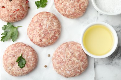 Photo of Many uncooked patties and spices on white marble table, flat lay