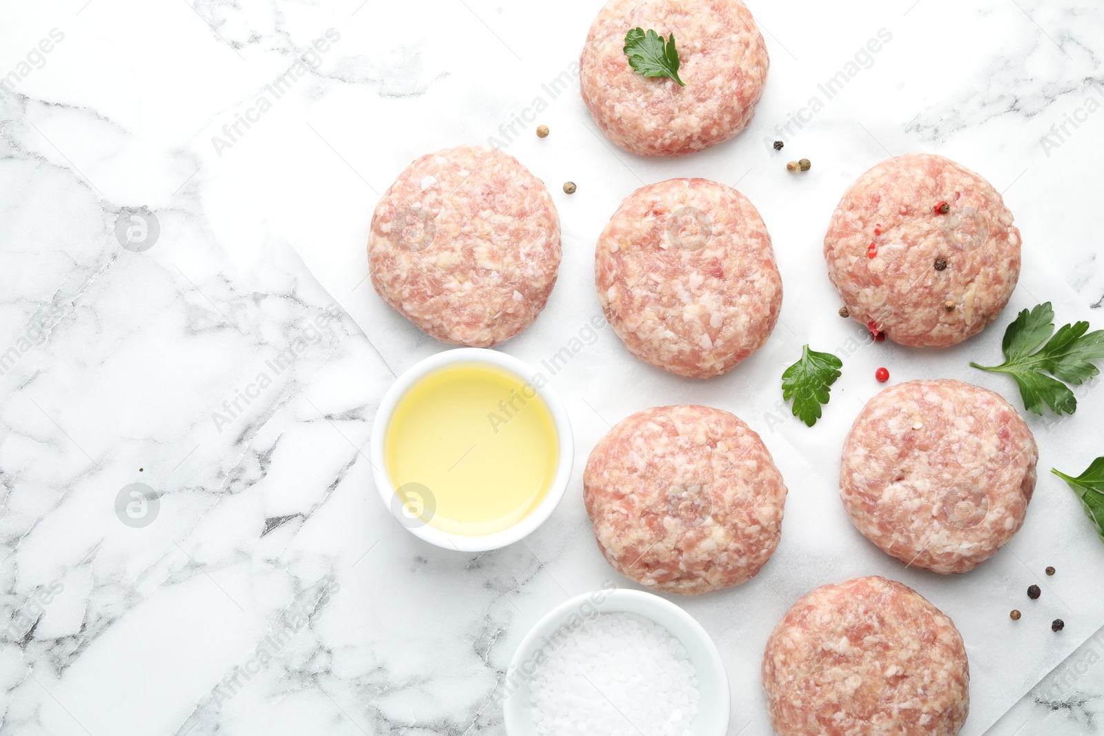 Photo of Many uncooked patties and spices on white marble table, flat lay. Space for text