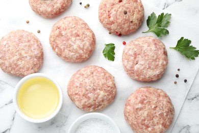 Photo of Many uncooked patties and spices on white marble table, flat lay