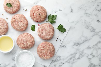 Photo of Many uncooked patties and spices on white marble table, flat lay. Space for text