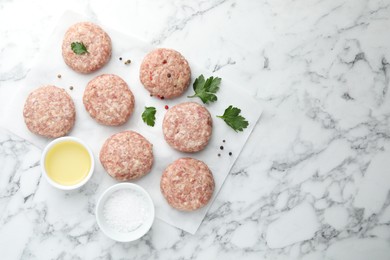 Photo of Many uncooked patties and spices on white marble table, flat lay. Space for text