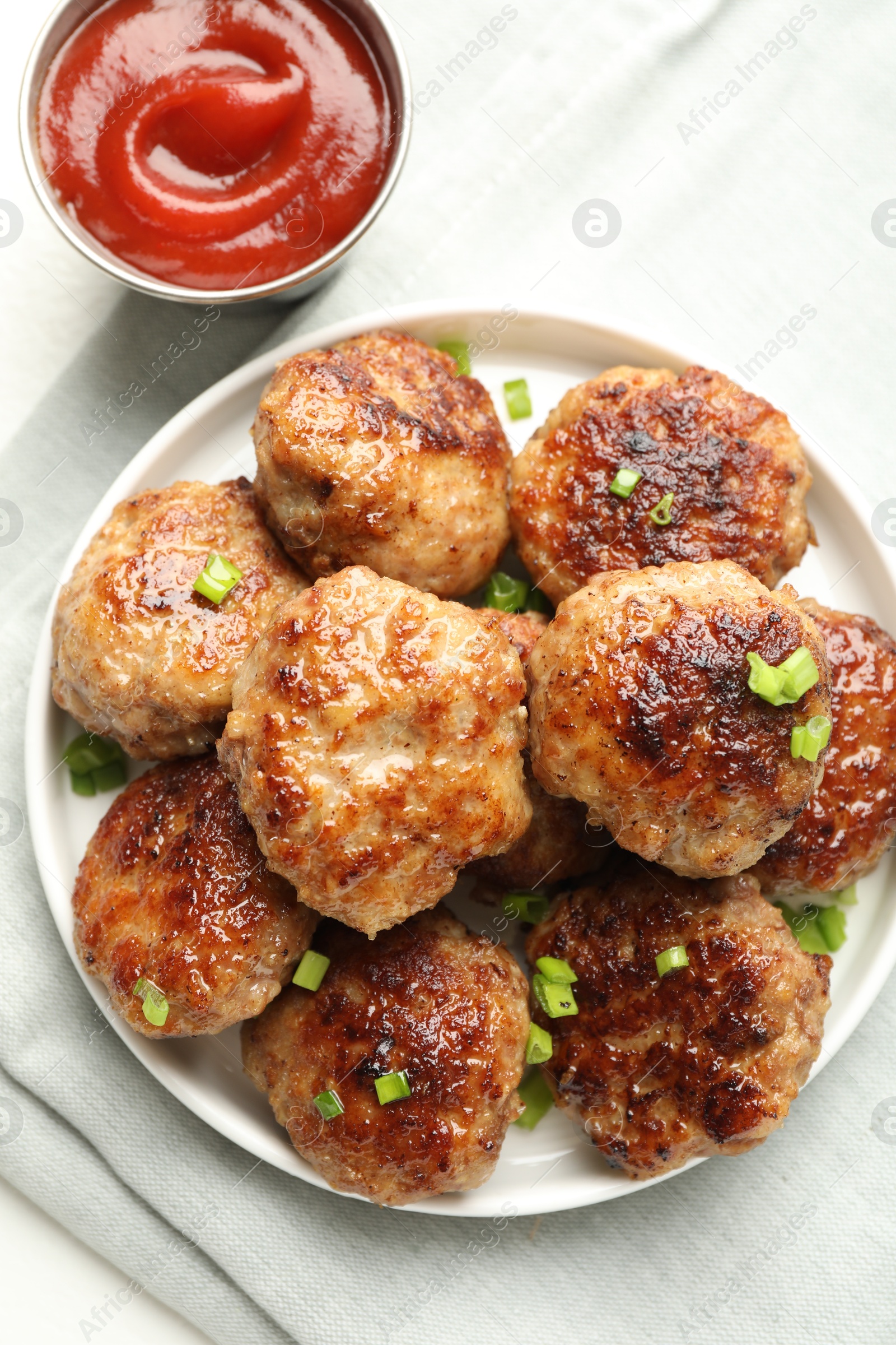 Photo of Delicious patties with green onions and ketchup on white table, top view