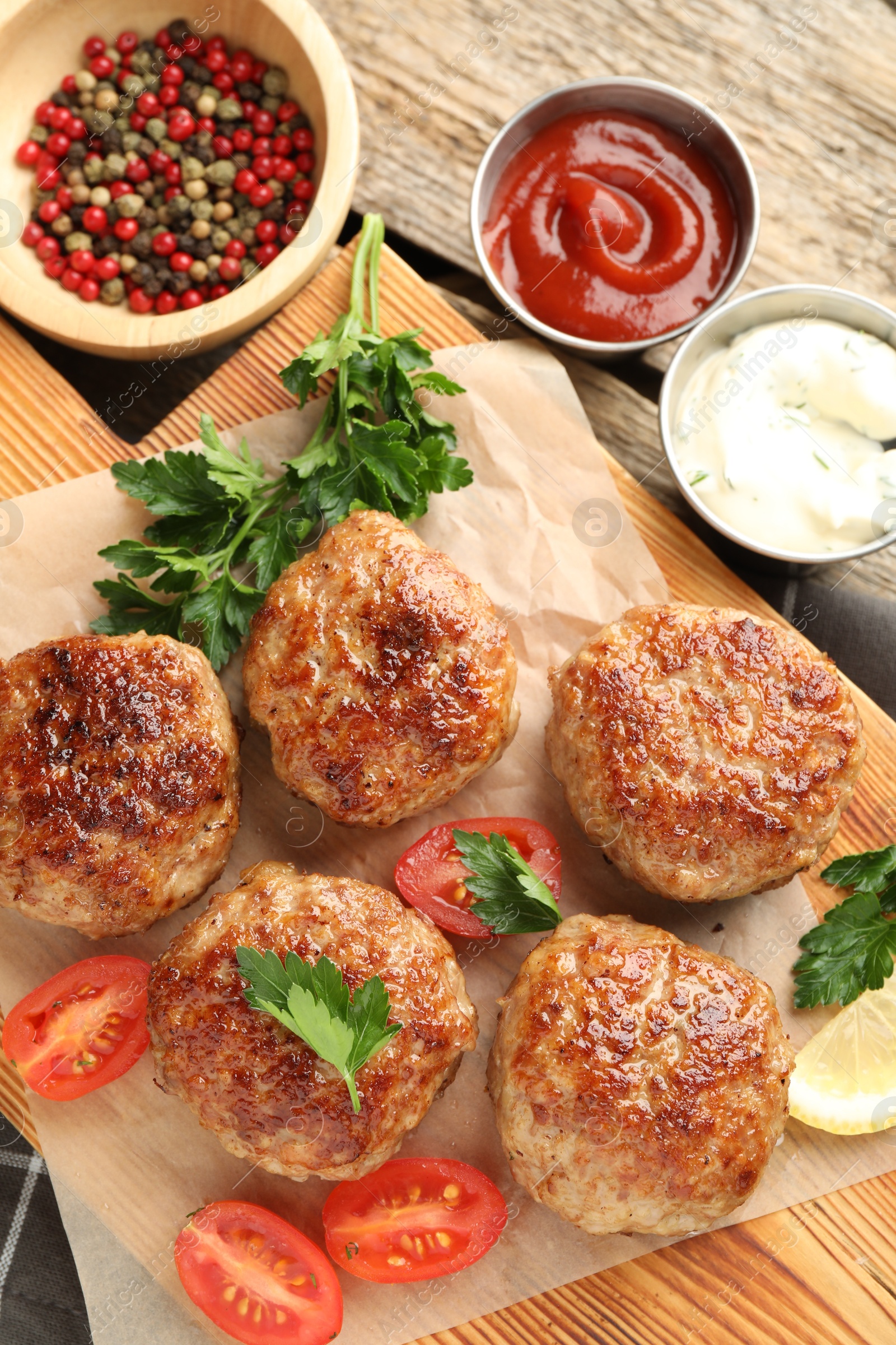 Photo of Delicious patties, spices, tomatoes and sauces on wooden table, flat lay