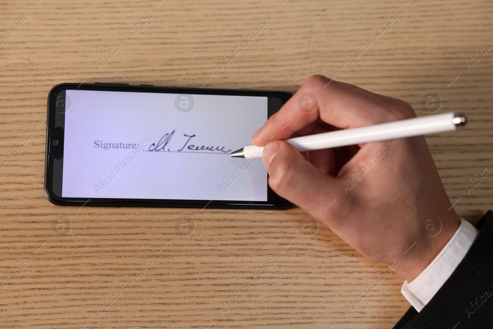 Photo of Electronic signature. Man using stylus and smartphone at wooden table, top view