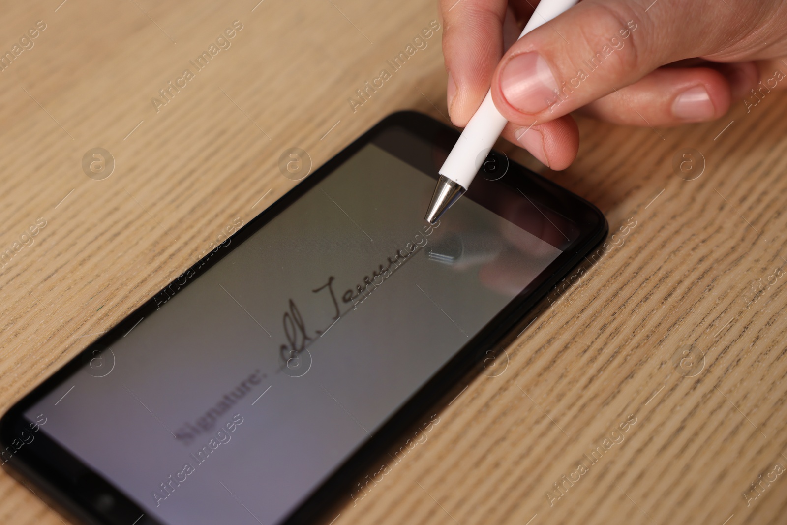 Photo of Electronic signature. Man using stylus and smartphone at wooden table, closeup